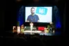 Kids.Doc-Kinderarzt bei Live-Bühnenshow vor Publikum, im Hintergrund Leinwand mit Hi-Sprechblase und Arzt im Kittel